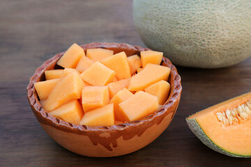 Whole and cut delicious ripe melons on wooden table, closeup