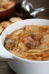 Tasty cabbage soup with meat and carrot on wooden table, closeup