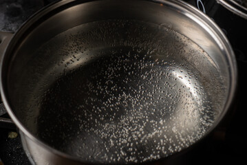 The water in the pot starts to boil. A saucepan on a gas stove with air bubbles from boiling water.