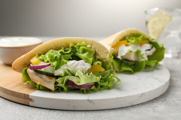Delicious pita sandwiches with chicken breast and vegetables on light gray table, closeup