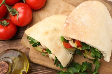 Delicious pita sandwich with grilled vegetables and parsley on wooden table, flat lay