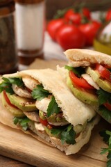 Delicious pita sandwich with grilled vegetables and parsley on wooden table, closeup