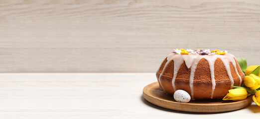 Delicious Easter cake decorated with sprinkles, egg and beautiful tulips on white wooden table, space for text. Banner design