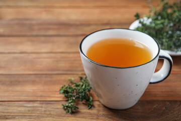 Aromatic herbal tea with thyme on wooden table, closeup. Space for text