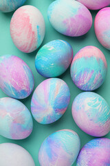 Many decorated Easter eggs on turquoise background, flat lay