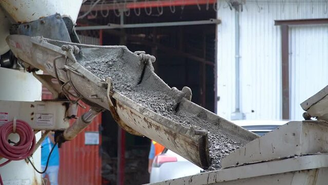 The production of cement, running down from a mixer machine, at a construction site. Handheld slow motion shot.

