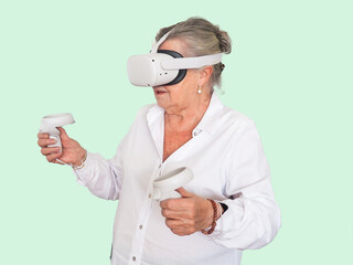 Elderly woman with gaming glasses and controls in the hands having fun