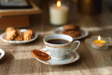 Scented candles, chocolate, cookies, cup of tea, books, e-reader, glasses and flowers on the table. Hygge at home. Selective focus.