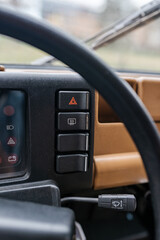 Interior shot of a classic car with a view of the dashboard, hazard button and windshield wiper