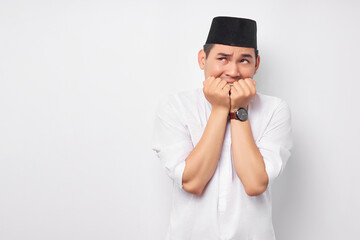 Anxiety problem. Portrait of afraid young Asian Muslim man in Arabic clothes looking stressed and nervous with hand on mouth isolated on white background. People religious Islamic lifestyle concept