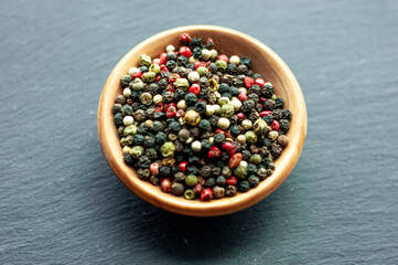 black red green white peppercorns, a mixture of peppers seasoning fragrant spice for fish meat close up on a black background