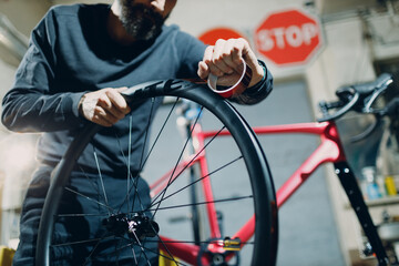 Mechanic repairman assembling wheel install tape sealant for bike tire custom bicycle in workshop