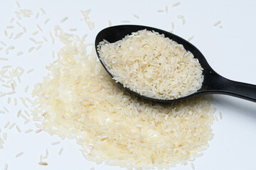 Biały ryż jaśminowy na czarnej łyżce  - obrazy, fototapety, plakaty