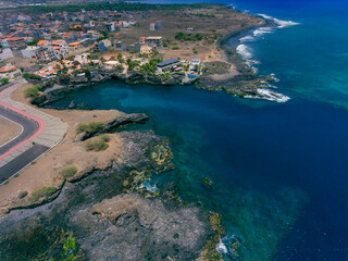 Fototapeta premium Aerial photos of Tarrafal in Santiago Island, Cabo Verde showcase the stunning beaches and clear waters of this idyllic coastal town, as well as its colorful buildings, charming streets