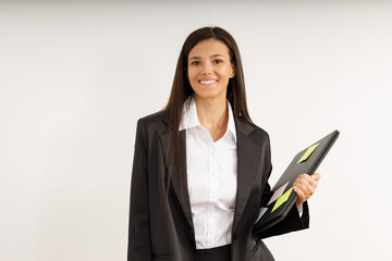 Portrait of happy smiling young woman with laptop in her hands, dressed in white shirt and black jacket on isolated white background. Studio shot of brunette girl with laptop computer.