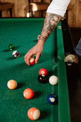 Handsome man is posing with billiard stick on the billiard table in the bar or salloon - 578649640