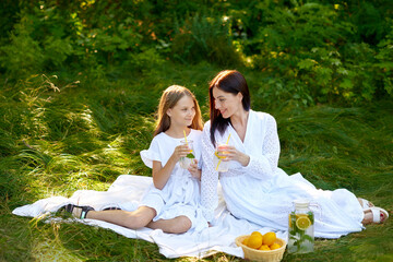 young mother and daughter enjoy time together on lemonade picnic in summer