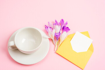 Obraz na płótnie Canvas Empty coffee cup, bouquet of spring flowers and envelope with blank card. Top view, mockup