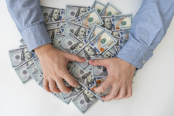 Man's hands and a lot of dollar bills on a white table. Bribes, corrupt, cash. US dollars in male...