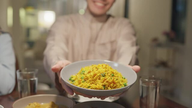 Close-up dish of biryani rice happy smile Asia muslim husband or son Ramadan dinner together show favorite halal food at home to the camera. Family celebration end of Eid al-Fitr togetherness at home.