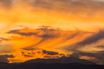 amazing clouds with storm during sundown in a flat landscape with a moutain