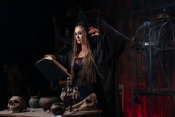 Halloween concept. Witch dressed black hood with dreadlocks standing dark dungeon room use magic...