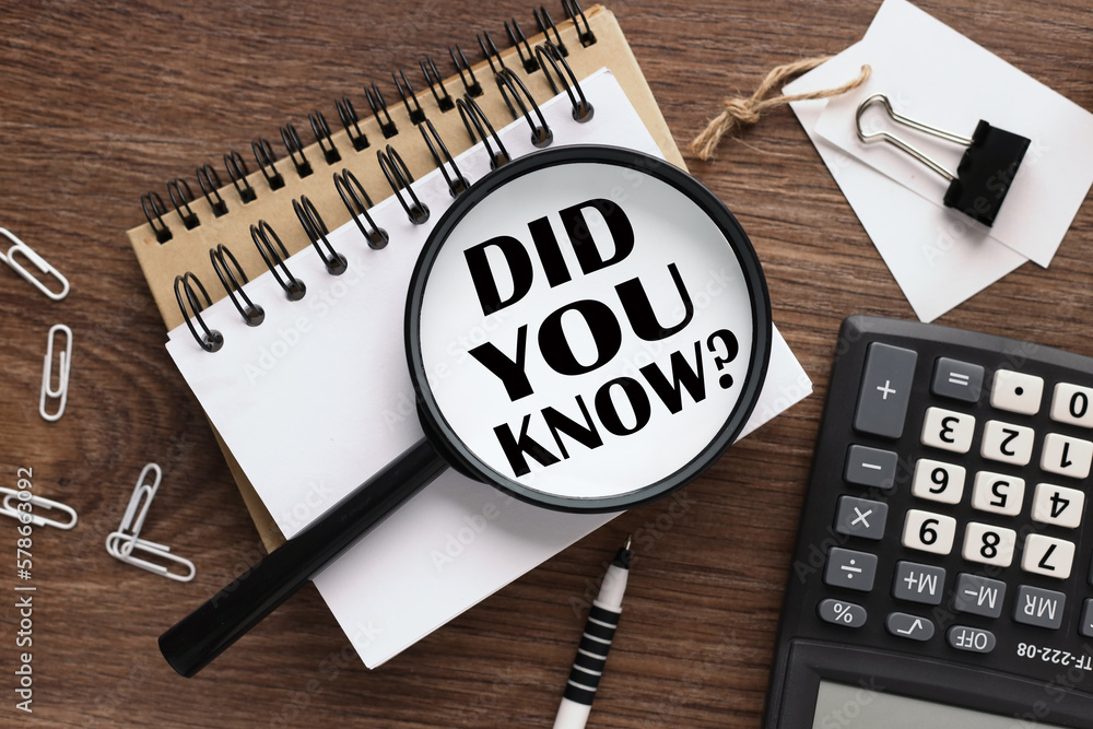 Poster did you know? wooden background with text on magnifier glass. two notepads and a calculator
