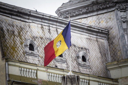 Romanian revolutionary flag with a hole, also called Drapelul Romaniei waiving on a flagpole of Timisoara. It is the national symbol of Romania, emblem of the 1989 romanian revolution ending up Commun