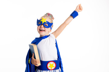 Smiled preschooler daughter model standing on white background wearing superhero superman costume posing with book in hands shooting process for back to school ready to go.