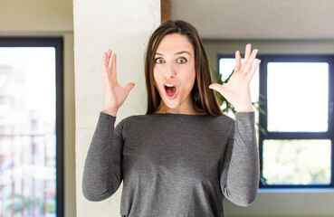 young adult pretty woman looking shocked and astonished, with jaw dropped in surprise when realizing something unbelievable