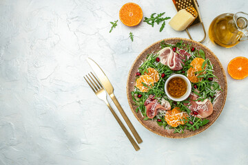 Delicious salad with arugula mandarins, prosciutto jamon and Parmesan cheese on blue background. Long banner format. top view