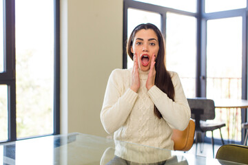 pretty caucasian woman feeling shocked and scared, looking terrified with open mouth and hands on cheeks