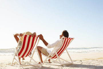 This is the life...A happy couple sitting in deck chairs on the beach together - Copyspace.