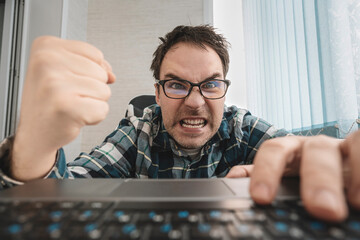 businessman in a shirt in the office punches the keyboard. angry man swearing and cursing against...