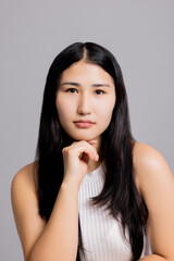 Serious beautiful cute asian confident serious woman in white casual shirt isolated on frey background female portrait. Natural make up.