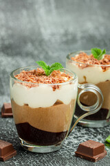 three chocolate in a glass jar decorated with mint on a dark background. Layered delicious dessert. vertical image. place for text