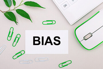 On a light background, a white calculator, a computer mouse, green paper clips, a green plant and a...