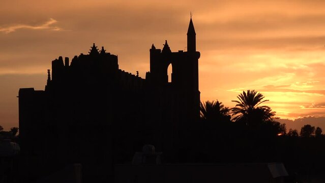 Colorful orange sunset and silhouette of partly damaged Lala Mustafa Mosque (formerly a cathedral) in Famagusta, religious landmarks in Northern Cyprus
