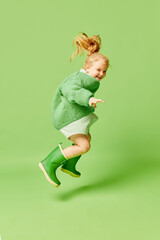 Happy smiling cute kid, little girl in fashionable look clothes and sunglasses jumping over light...