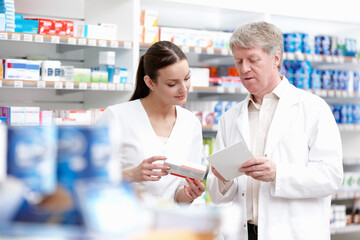 Pharmacists checking the medicine from the prescription. Portrait of careful male and female pharmacists checking the medicines at store.