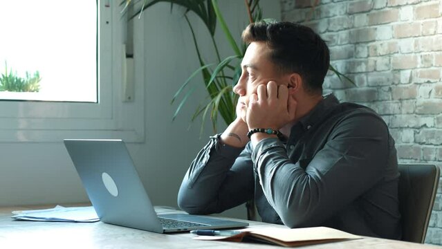 Tired male student or worker sit at home office desk look in distance having sleep deprivation, lazy millennial man distracted from work feel lazy lack motivation, thinking of dull monotonous job
