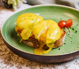 Classic egg benedict on green plate