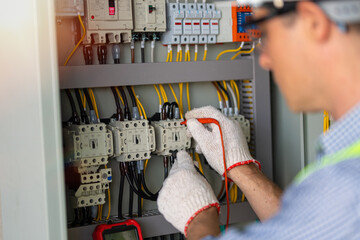 Electrician engineer work tester measuring voltage and current of power electric line in electical cabinet control.and wires on relay protection system. Bay control unit. Medium voltage switchgear. - obrazy, fototapety, plakaty