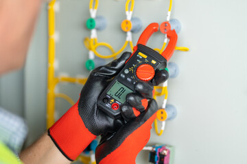 Electrician installing electrical wires and multimeter fuse switch box in hands of electrician...
