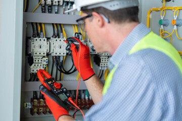 Fototapeta premium Electrician installing electrical wires and multimeter fuse switch box in hands of electrician detail