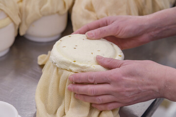 A man holds ripening cheese in special cloth.