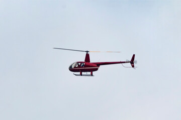 A small red helicopter flying in sky
