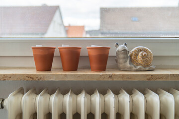 Three terracotta pots on the windowsill with the figure of a snail
