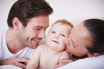 Doting on their little one. Two loving young parents spending time with their adorable baby girl indoors.