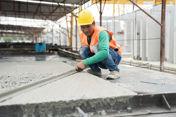 Construction technician working by leveling concrete floor to smooth. Construction worker uses long trowel spreading wet concrete pouring at construction site. Mason making smooth surface of concrete